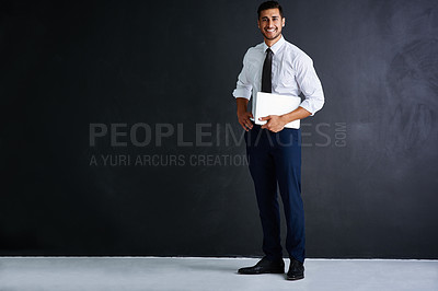 Buy stock photo Studio portrait of a young businessman standing against a black background