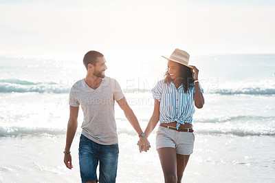 Buy stock photo Shot of a young couple walking along the beach