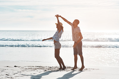 Buy stock photo Shot of a young couple dancing together at the beach