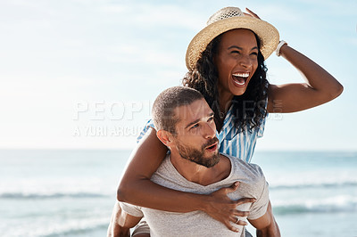 Buy stock photo Shot of a young man piggybacking his girlfriend at the beach