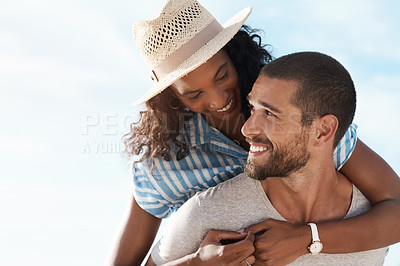 Buy stock photo Shot of a young man piggybacking his girlfriend at the beach