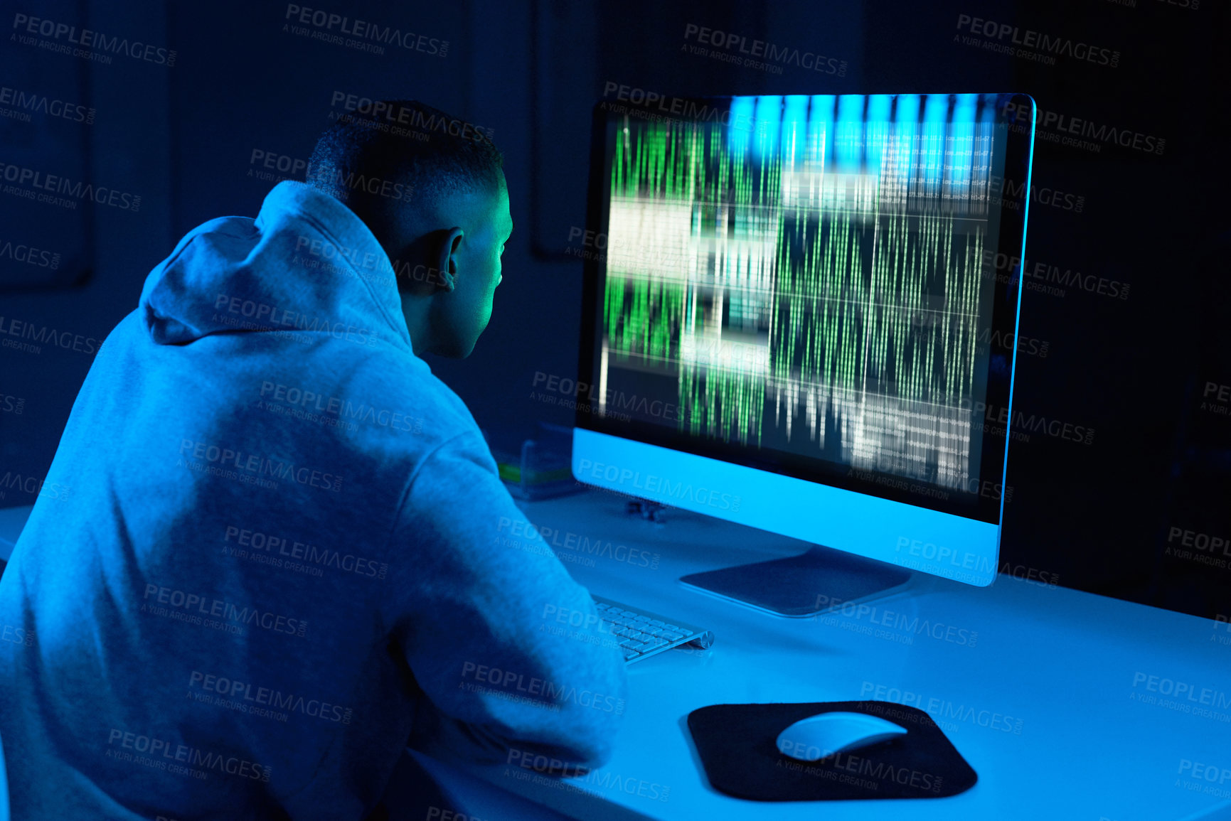 Buy stock photo Shot of a young male hacker cracking a computer code in the dark