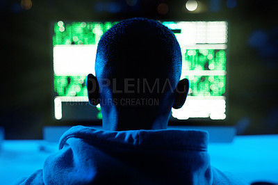 Buy stock photo Rearview shot of a male hacker cracking a computer code in the dark