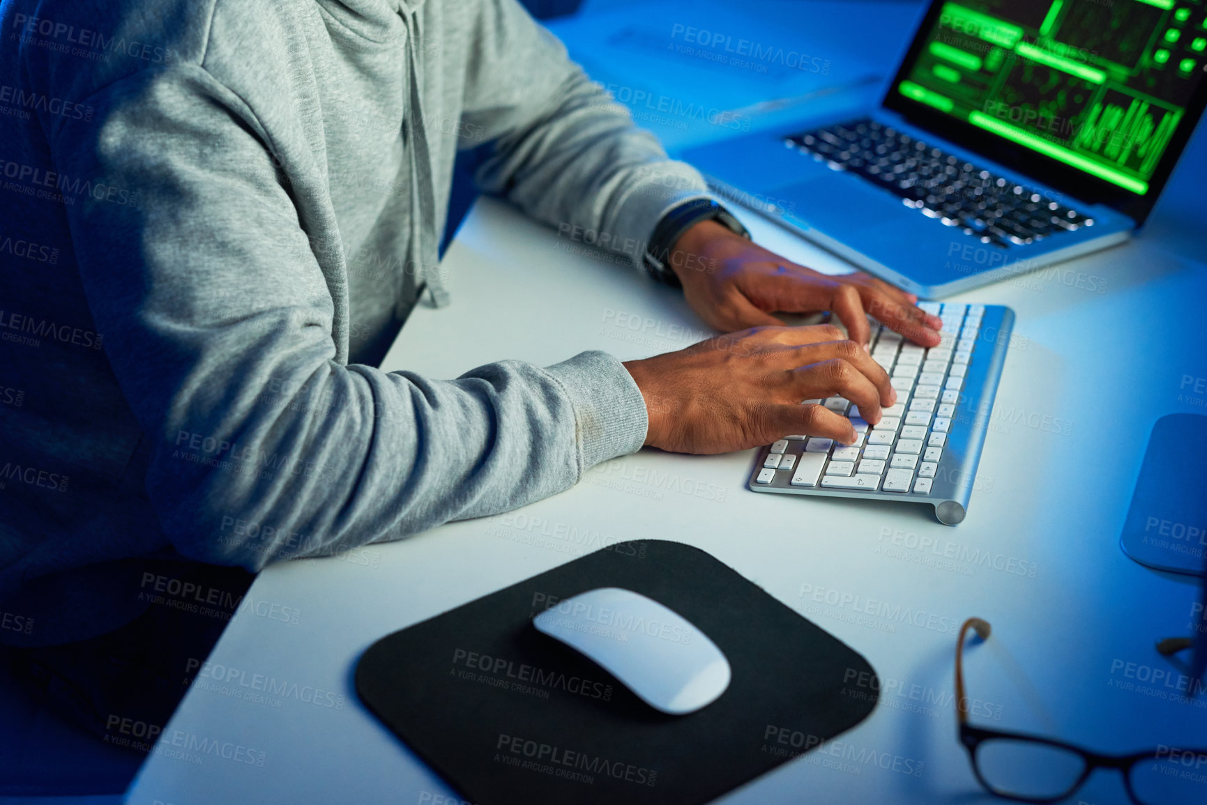 Buy stock photo Shot of an unrecognizable hacker cracking a computer code in the dark