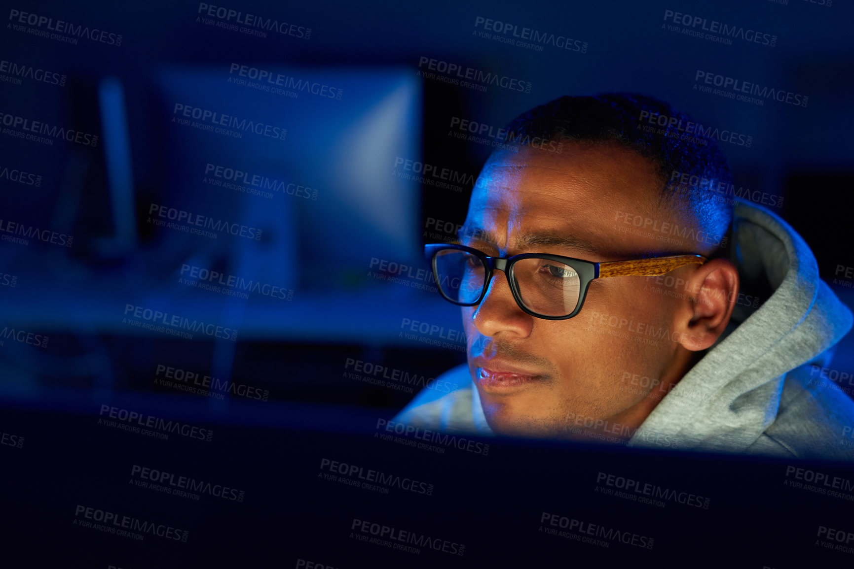 Buy stock photo Shot of a young male hacker cracking a computer code in the dark