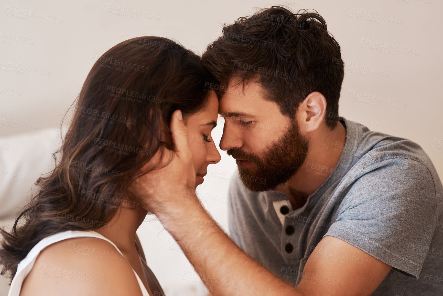 Buy stock photo Shot of an affectionate young couple sharing a romantic moment in the bedroom at home