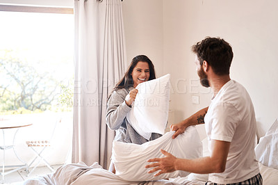 Buy stock photo Love, home bedroom and happy couple in pillow fight battle for fun, morning game or playing together. Happiness, excited energy and marriage man, woman or people smile for playful combat on bed