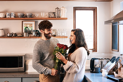 Buy stock photo Couple, roses and smile in kitchen for happy, in love and valentines day for support and care on holiday. Man, woman and flower bouquet for surprise and romantic in house for trust, joy or affection 