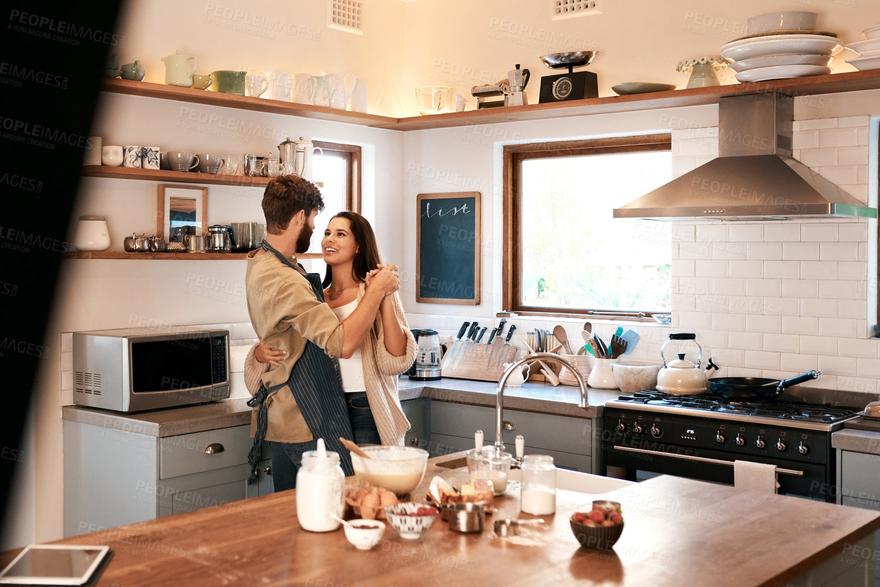 Buy stock photo Happy young couple, dancing and kitchen in home with love, comic moment and cooking together with romance. Man, woman and smile with dance, moving and happiness for food, nutrition or diet in house