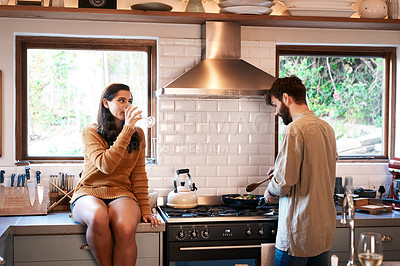 Buy stock photo Cooking, couple and wine in a kitchen at home with food at a stove drinking alcohol. Young woman, man and drinks in a house together making dinner with bonding, love and care for eating a meal