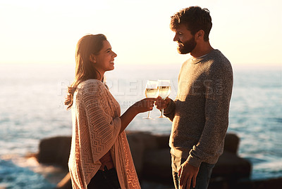 Buy stock photo Shot of a happy young couple toasting with wine at the beach