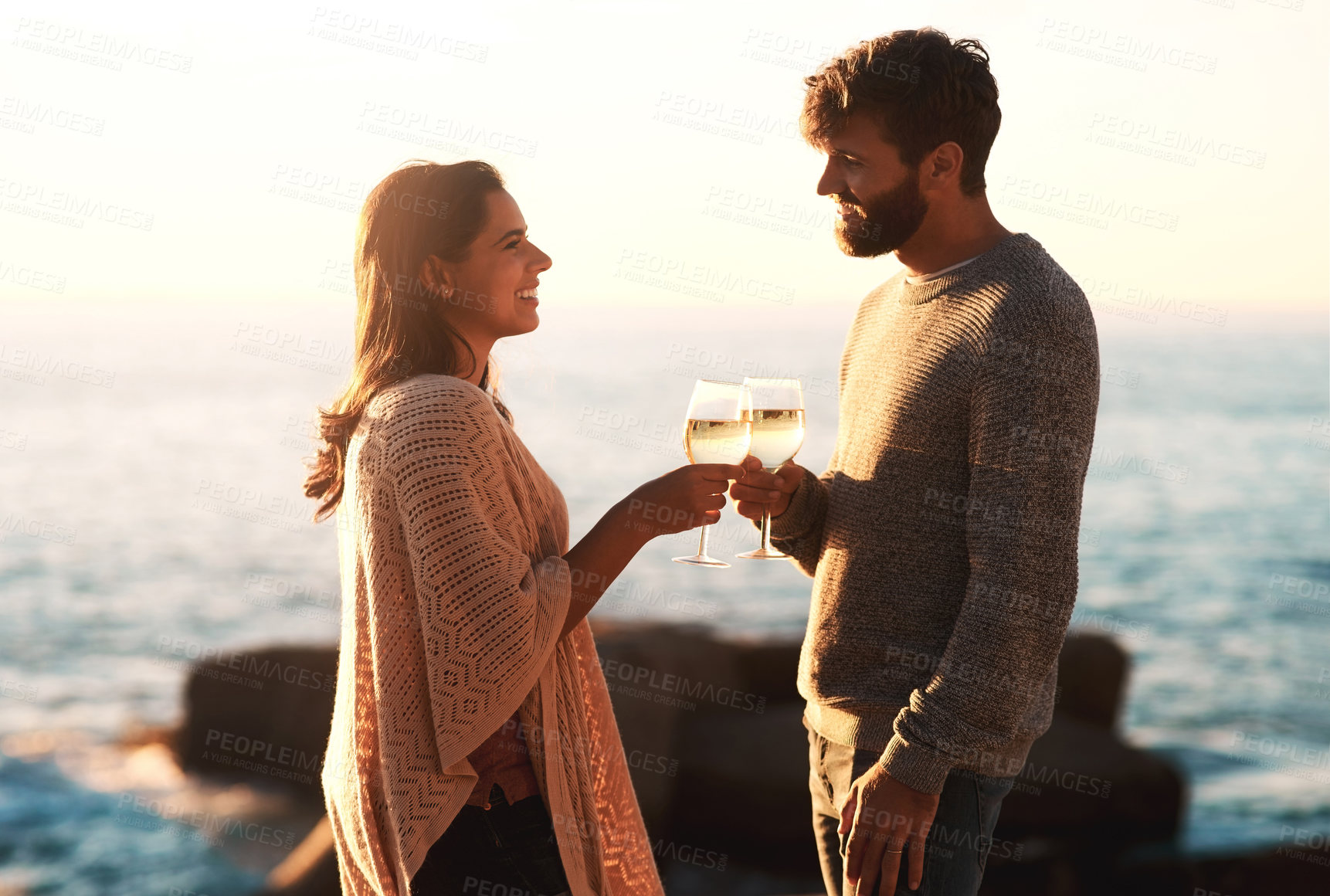 Buy stock photo Shot of a happy young couple toasting with wine at the beach