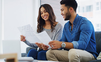 Buy stock photo Cropped shot of an happy young couple sitting on the sofa while going through paperwork in their lounge