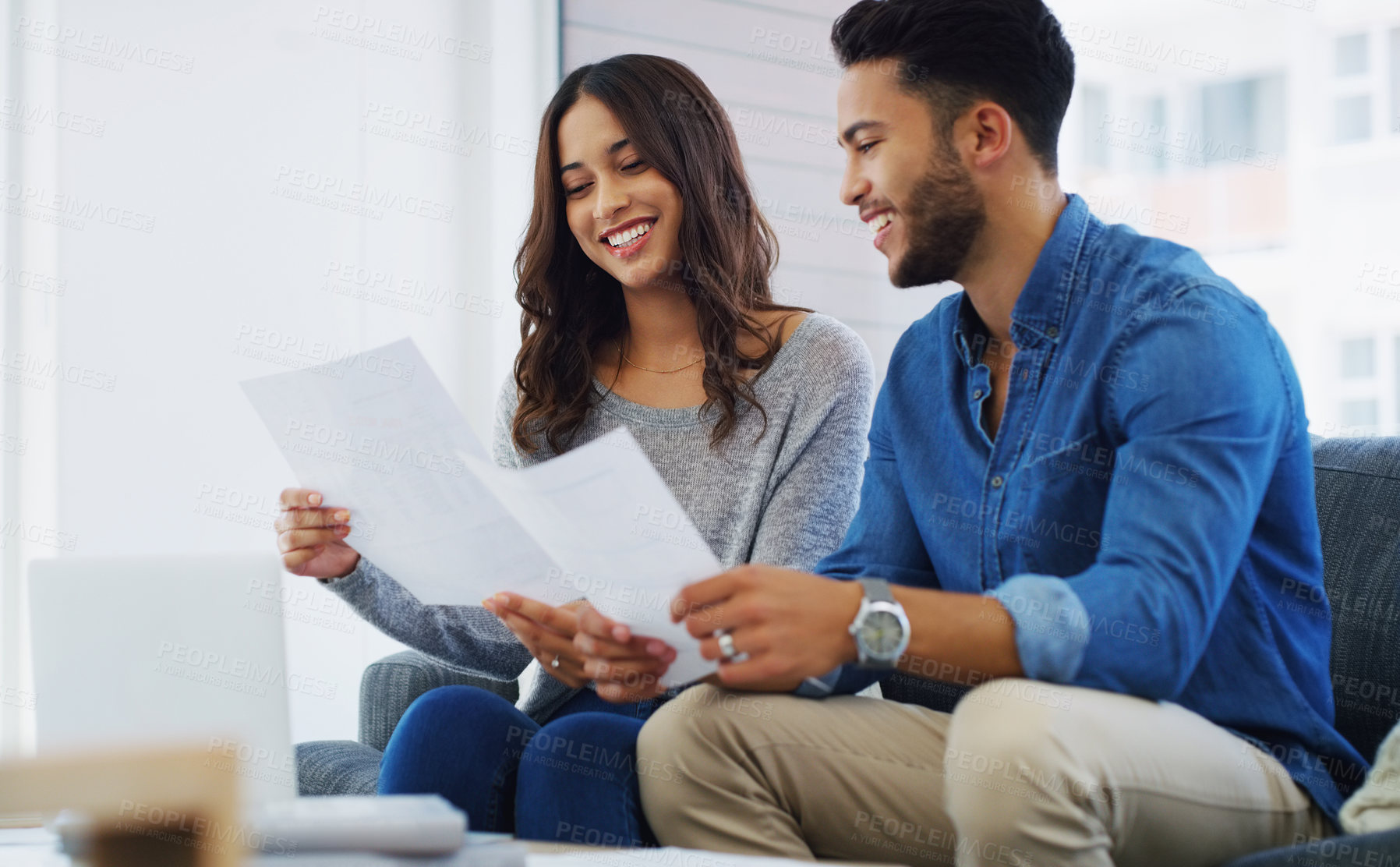 Buy stock photo Cropped shot of an happy young couple sitting on the sofa while going through paperwork in their lounge