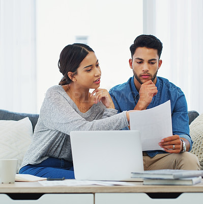 Buy stock photo Cropped shot of a young couple sitting on the sofa while going through paperwork in their lounge