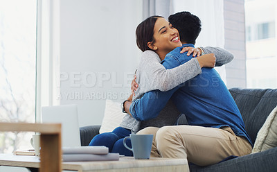 Buy stock photo Cropped shot of an affectionate young couple sitting on the sofa and hugging each other while in their lounge