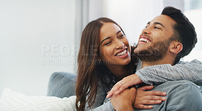 Buy stock photo Cropped shot of an affectionate young couple cuddling with each other while in their living room during the day