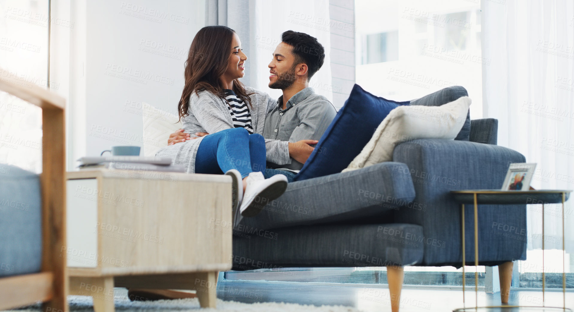 Buy stock photo Cropped shot of an affectionate young couple cuddling with each other while in their living room during the day