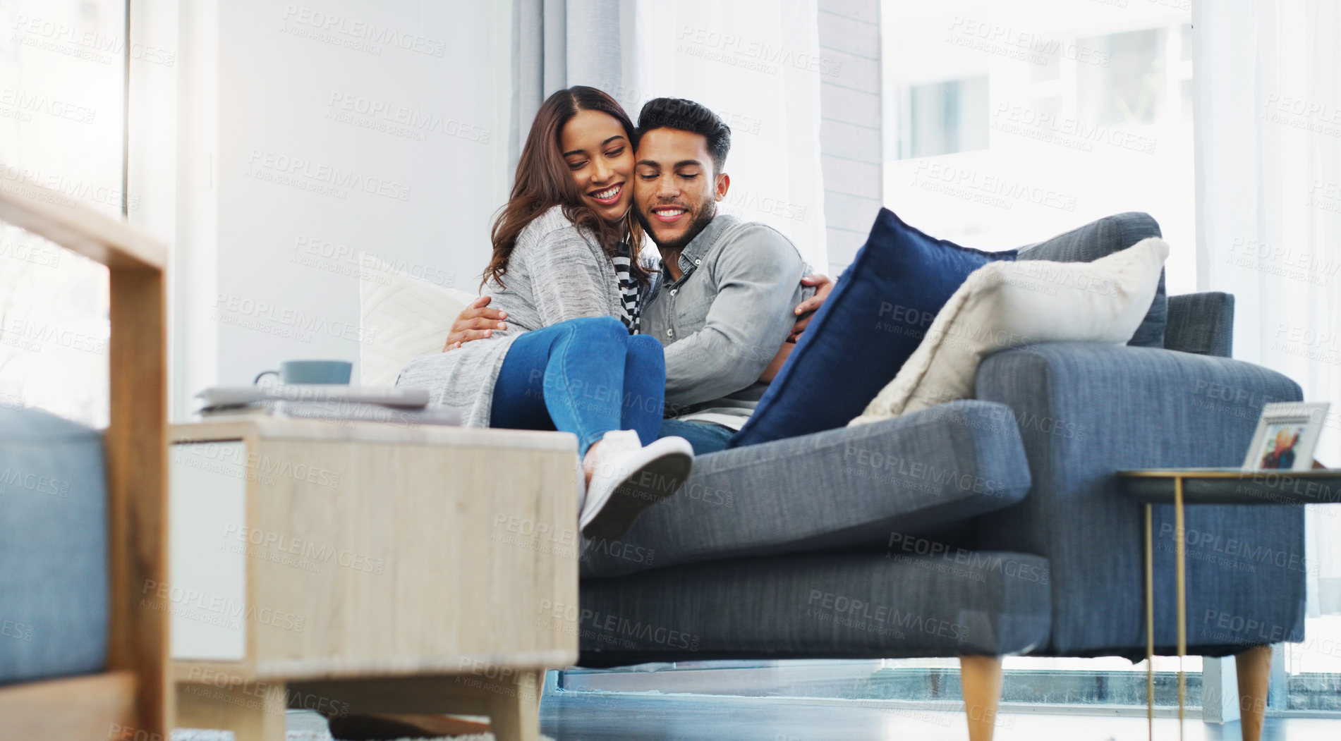 Buy stock photo Cropped portrait of an affectionate young couple cuddling with each other while in their living room during the day