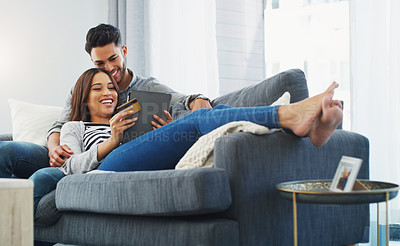 Buy stock photo Full length shot of an affectionate young couple lounging on the sofa while using a tablet in their living room