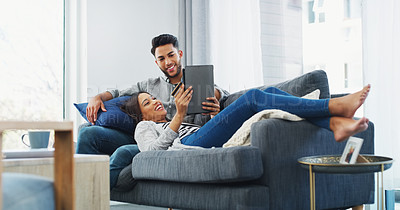 Buy stock photo Full length shot of an affectionate young couple lounging on the sofa while using a tablet in their living room