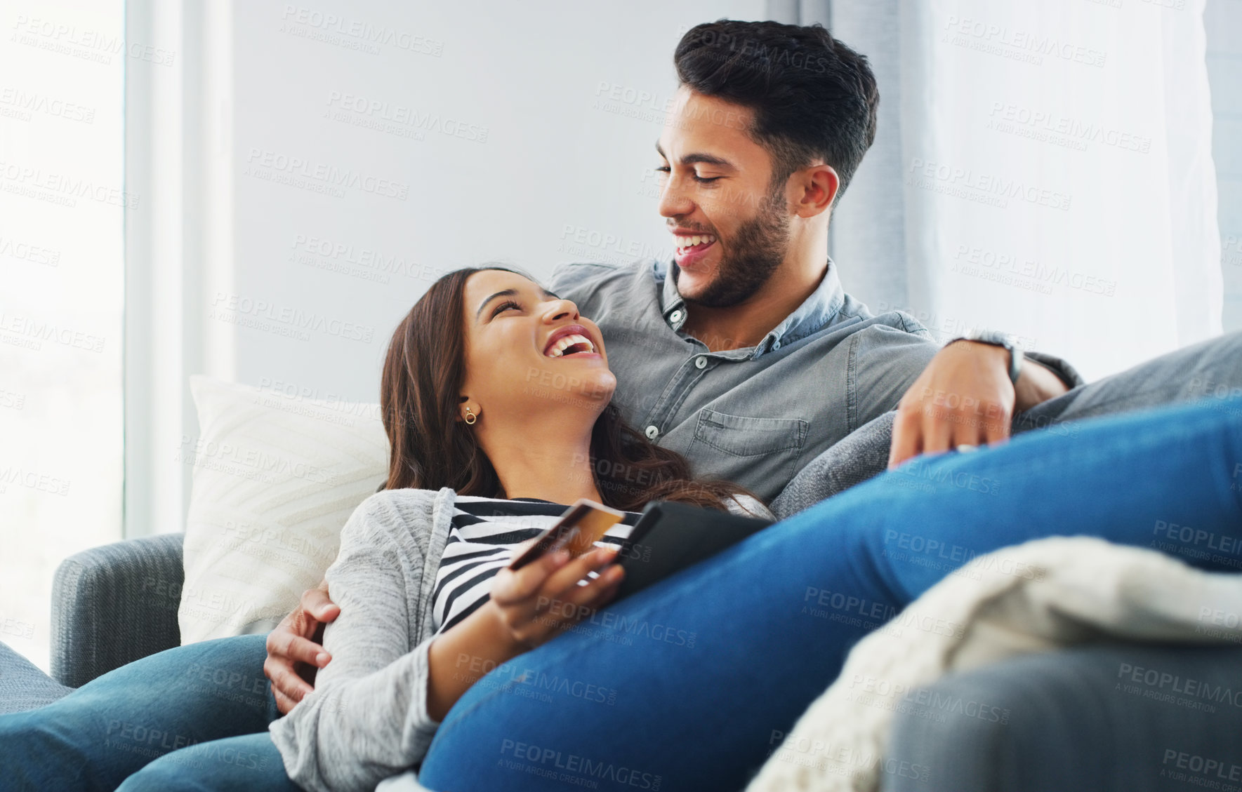 Buy stock photo Cropped shot of an affectionate young couple lounging on the sofa while using a tablet in their living room