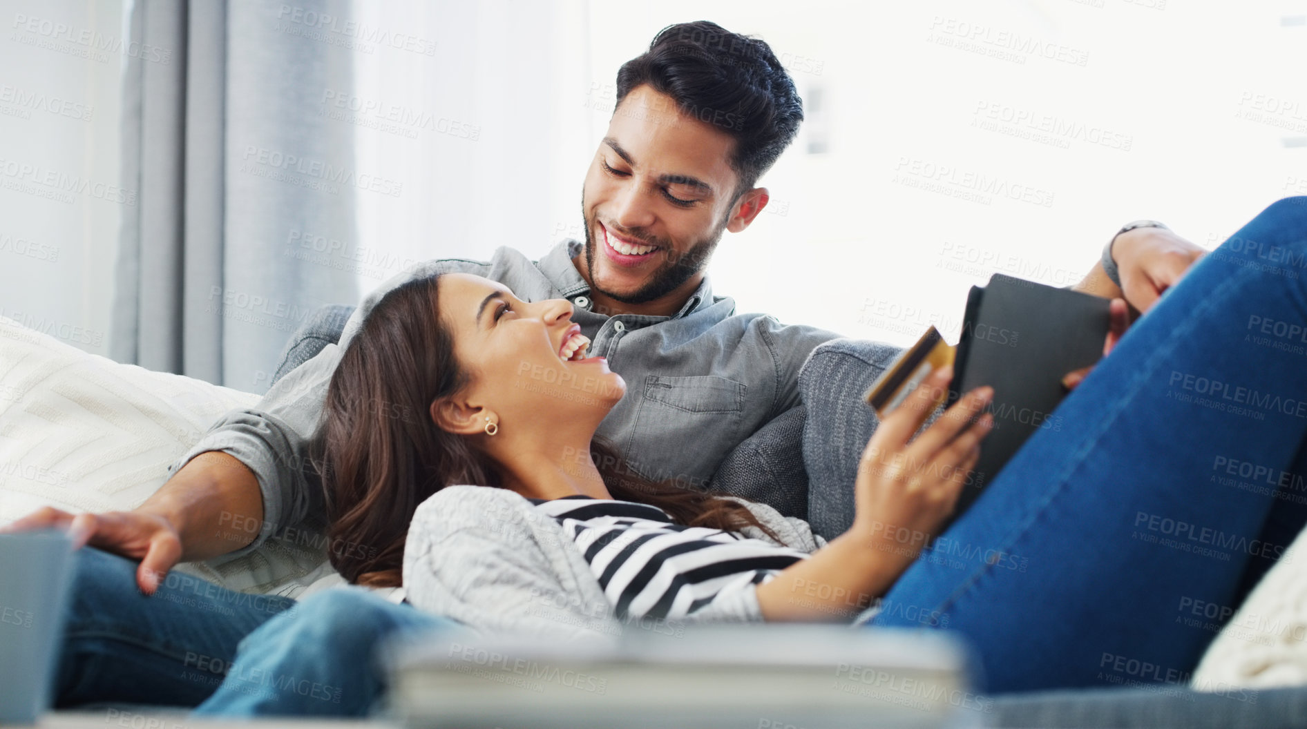 Buy stock photo Cropped shot of an affectionate young couple lounging on the sofa while using a tablet in their living room