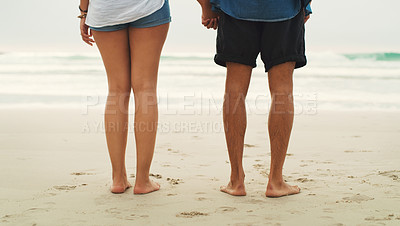 Buy stock photo Cropped rearview shot of an unrecognizable couple standing next to each other on the beach during the day