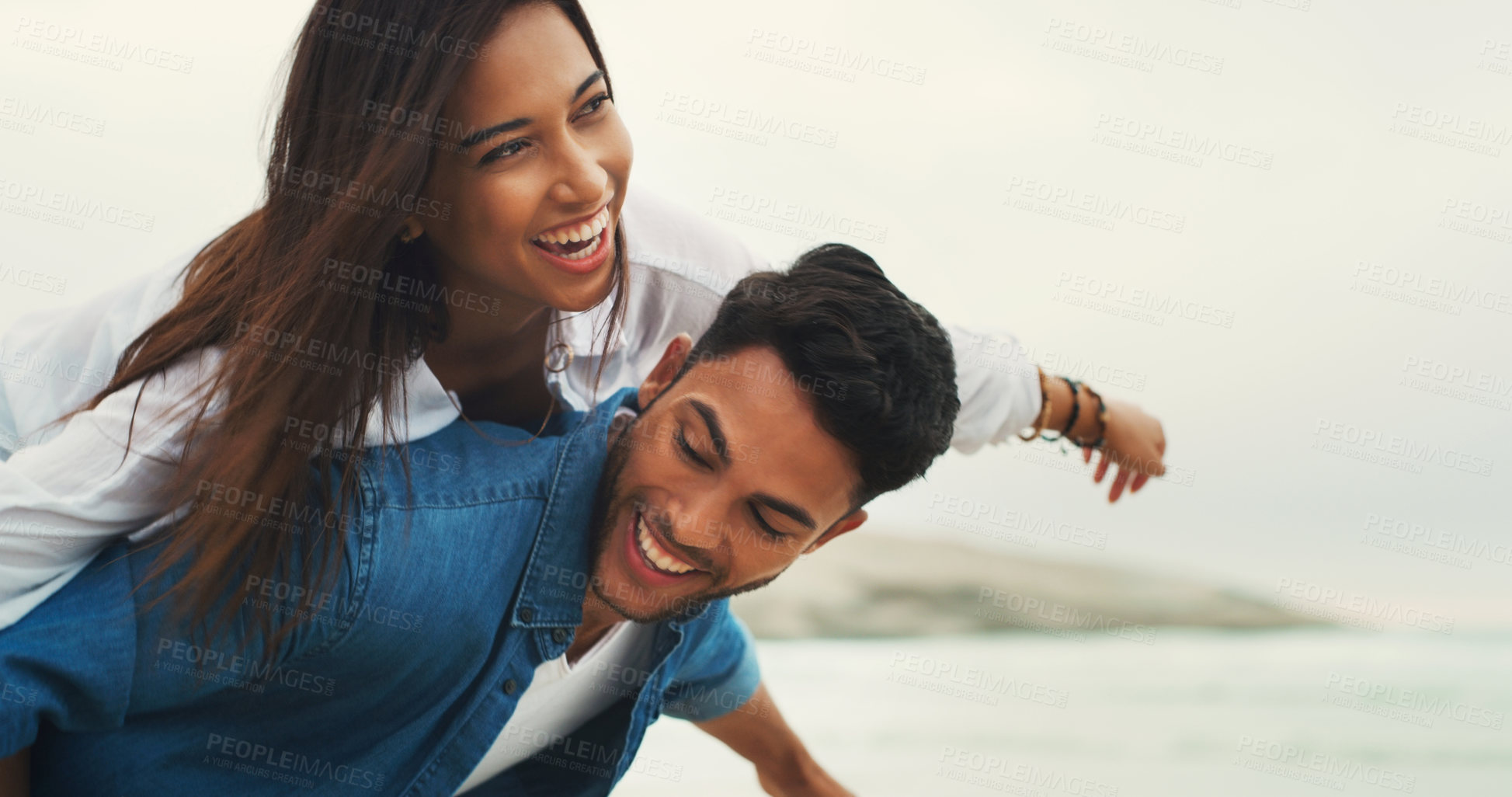 Buy stock photo Cropped shot of a playful young couple enjoying their time together on the beach during the day