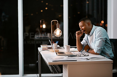 Buy stock photo Shot of a handsome young businessman yawning and feeling tired while working late in his office