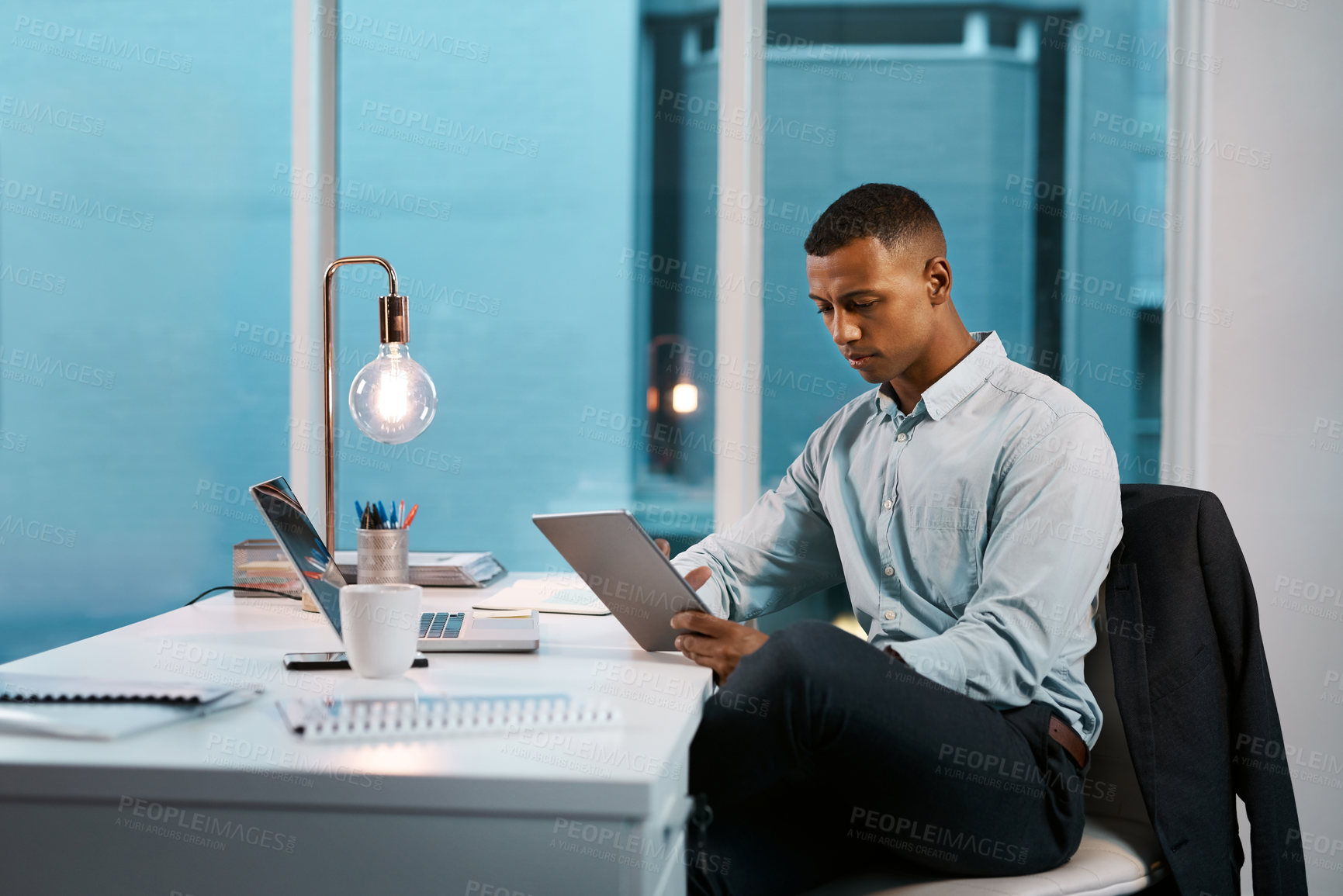 Buy stock photo Business, black man and research on tablet at office on desk with research for task in Atlanta. Male person, light bulb and night as project manager on updating data or information on company finance