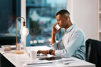 Buy stock photo Shot of a handsome young businessman taking phone call while working late in his office