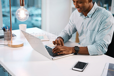Buy stock photo Shot of a handsome young businessman working on his laptop during a late night shift at work