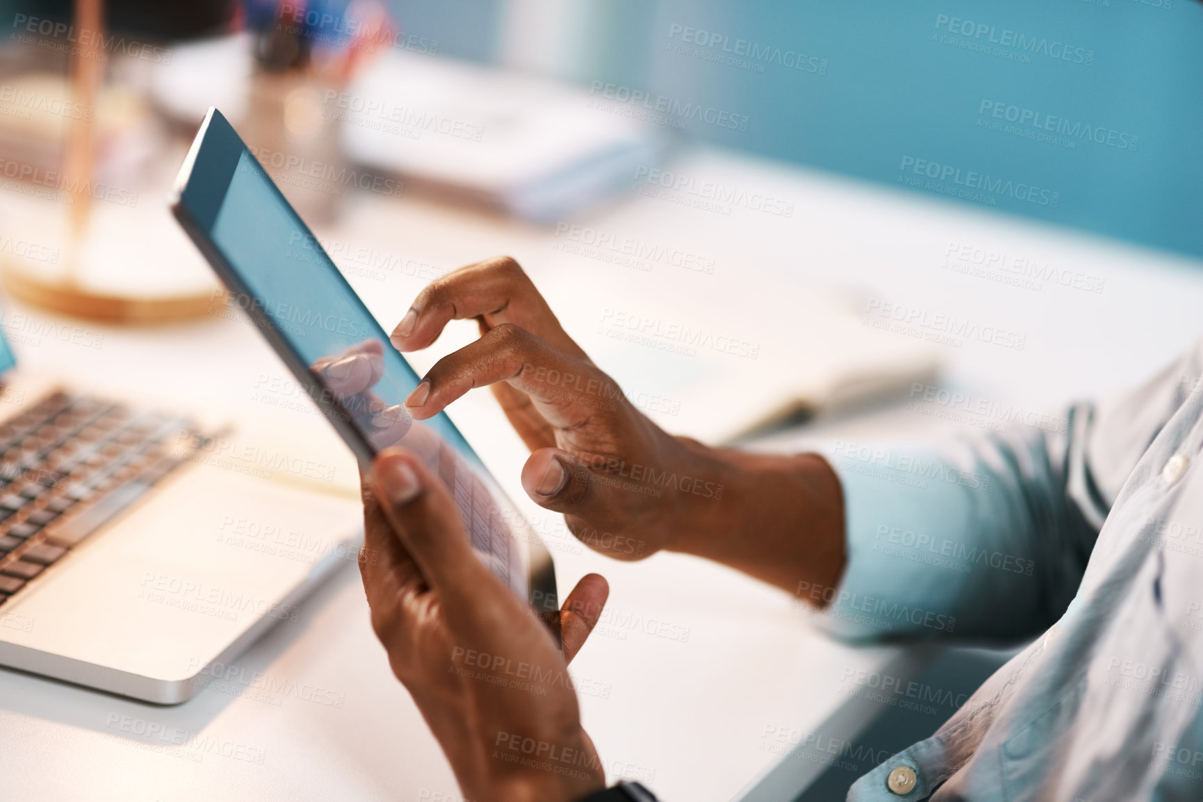 Buy stock photo Shot of an unrecognizable businessman using a digital tablet while working late in his office