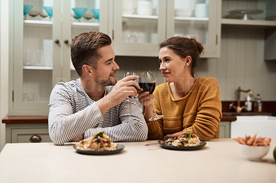 Buy stock photo Shot of an affectionate young couple making a toast while having a meal in their kitchen at home