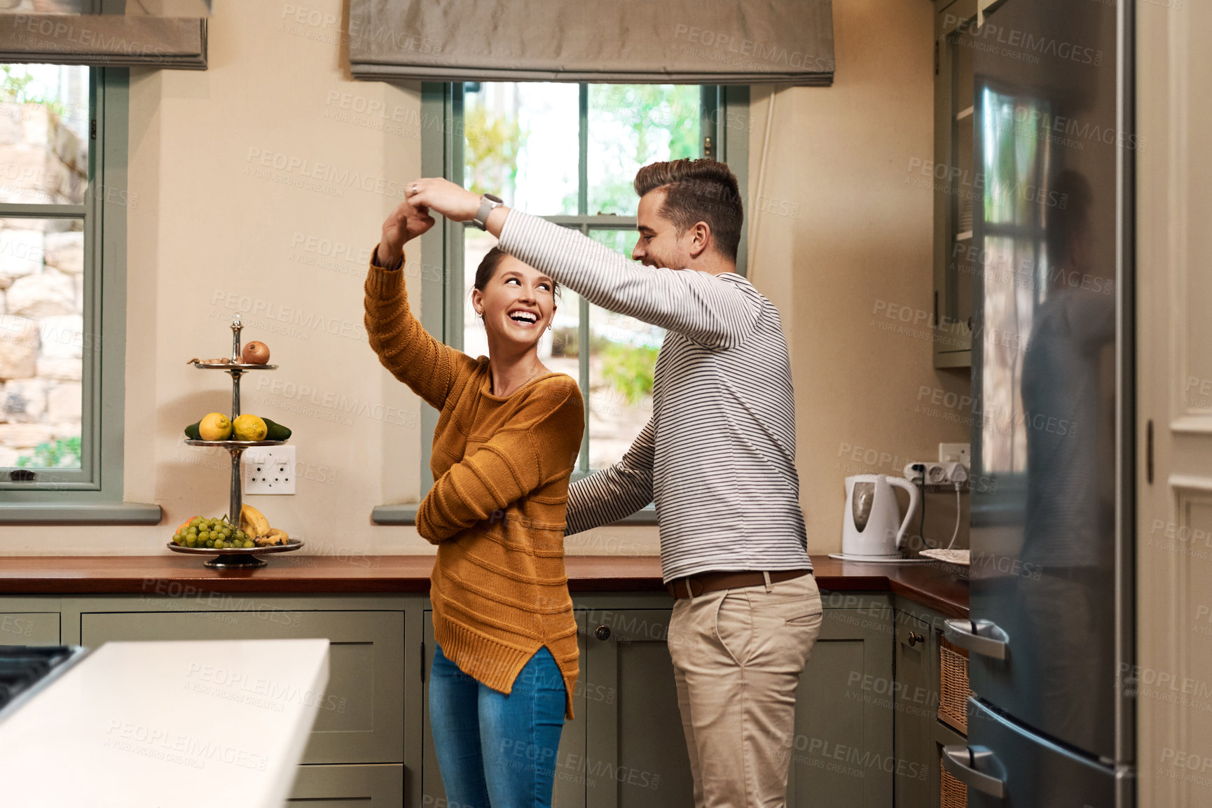 Buy stock photo Shot of an affectionate young couple dancing together in their kitchen at home