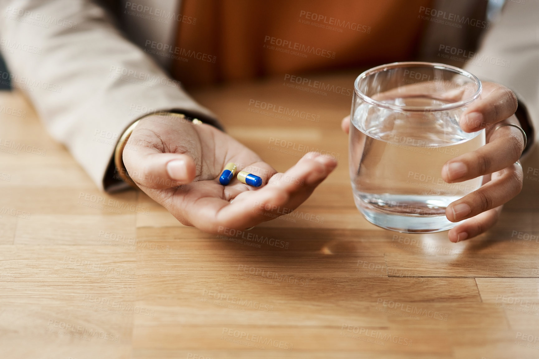 Buy stock photo Cropped shot of an unrecognizable businesswoman taking pills with a glass of water while in her office
