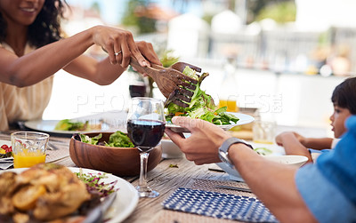 Buy stock photo Shot of an unrecognizable woman dishing up salad on her husband's plate while enjoying a meal with family outdoors