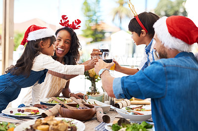 Buy stock photo Shot of a beautiful young family sharing a toast while enjoying Christmas lunch together outdoors