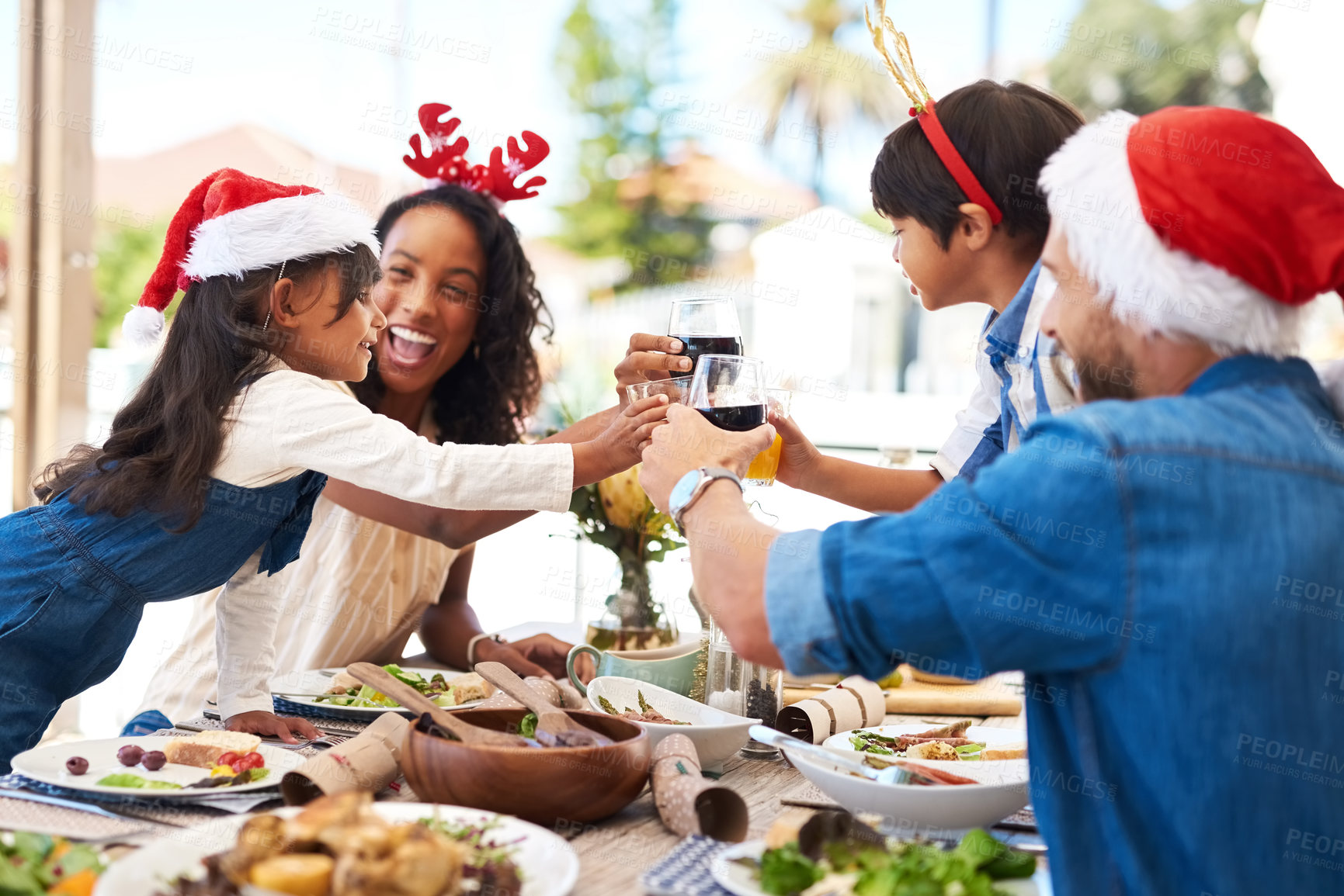 Buy stock photo Shot of a beautiful young family sharing a toast while enjoying Christmas lunch together outdoors