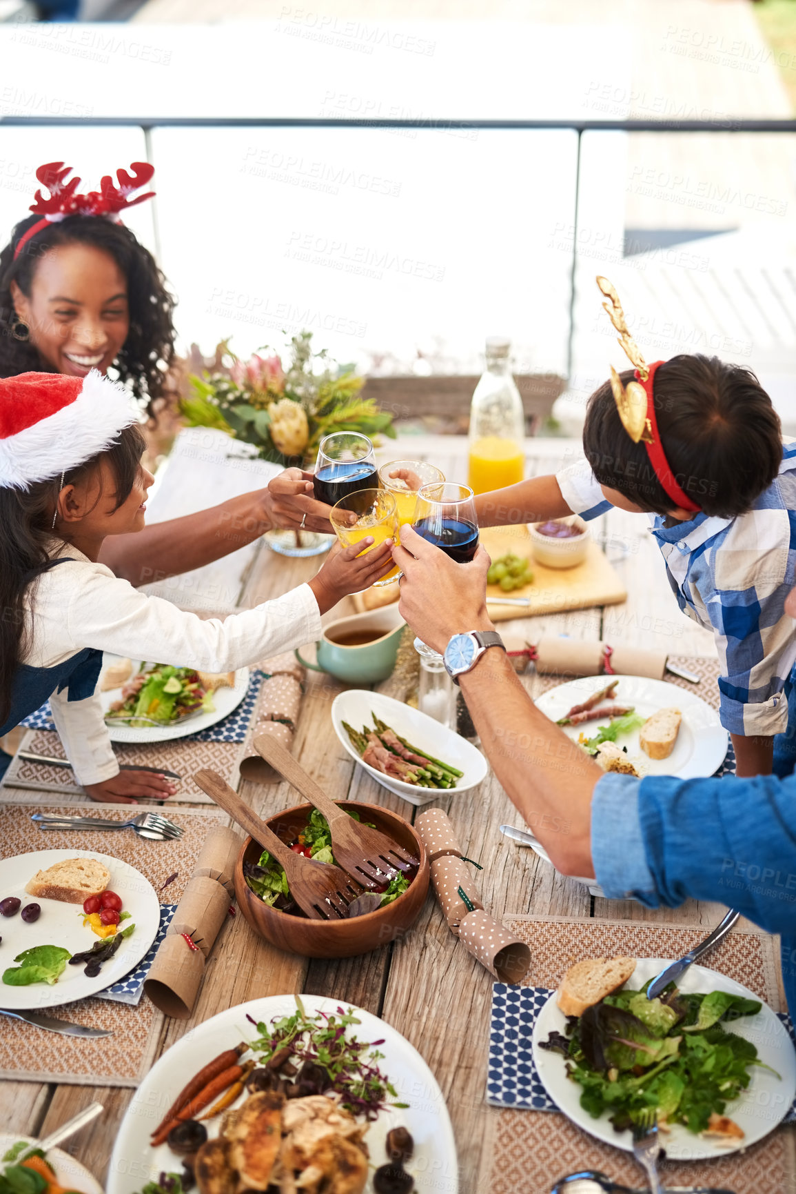Buy stock photo High angle shot of a beautiful young family sharing a toast while enjoying Christmas lunch together outdoors