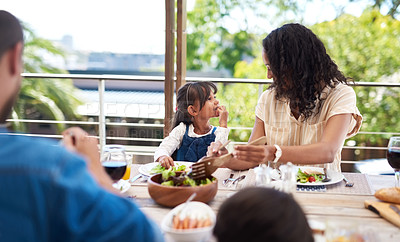 Buy stock photo Shot of an adorable little girl and her mother enjoying themselves during a meal with family outdoors