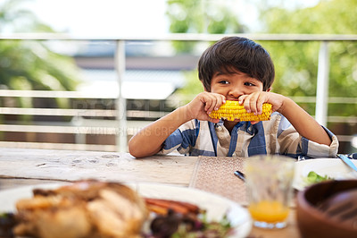 Buy stock photo Home, lunch and child with corn at backyard for healthy vegetables, nutrition and development. Outdoor, house and boy kid with food by table for afternoon meal, vitamins and eating of nutrients