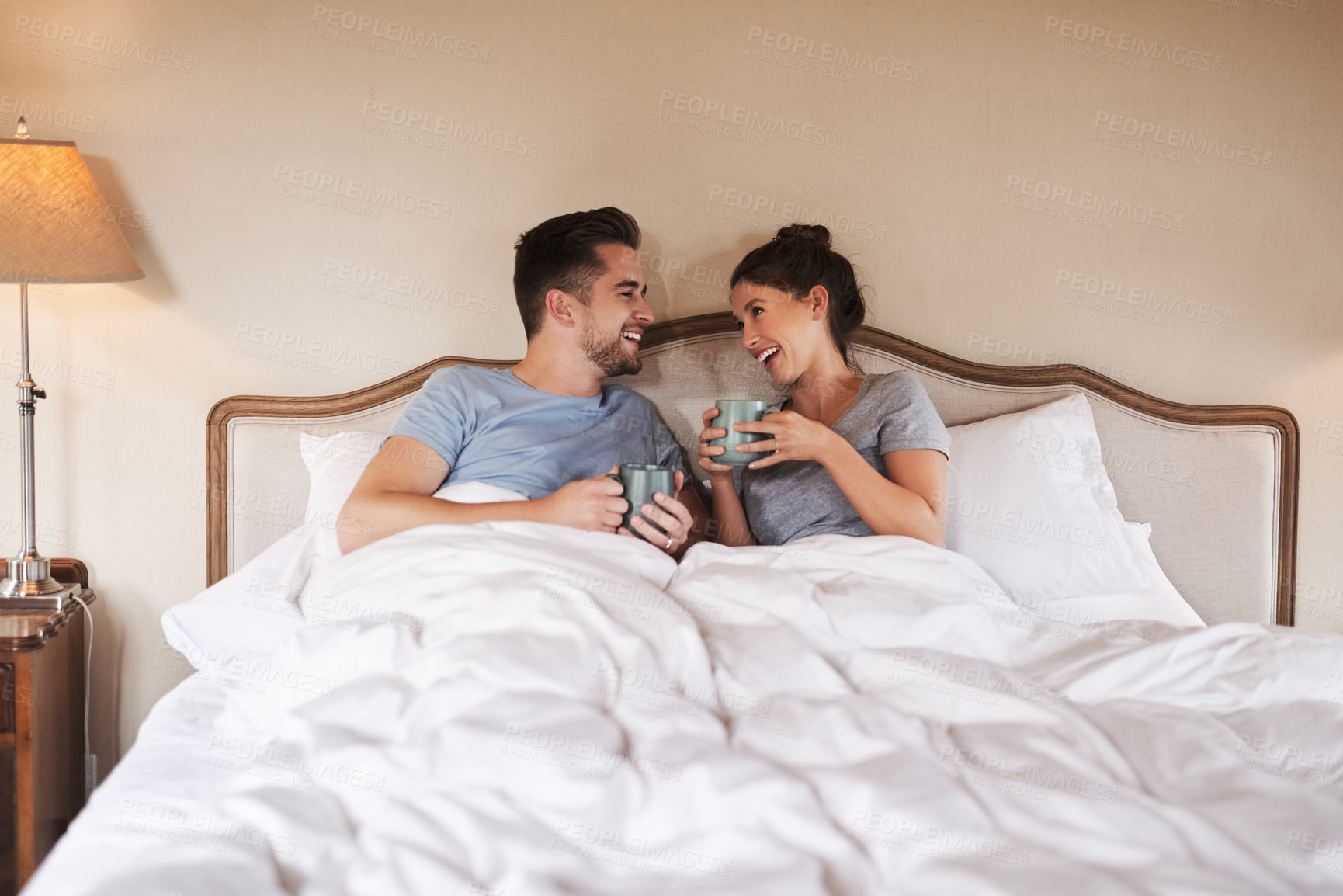 Buy stock photo Couple, bed and morning laugh with coffee, care and commitment together at home with funny joke. Love, marriage and anniversary with silly, fun and happy people with romance and duvet in bedroom