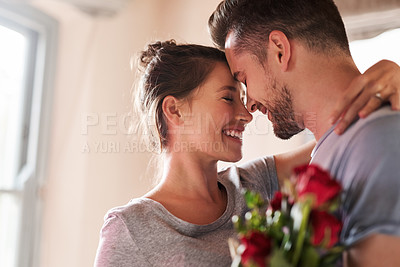 Buy stock photo Shot of a young man surprising his girlfriend with a bunch of roses in their bedroom at home