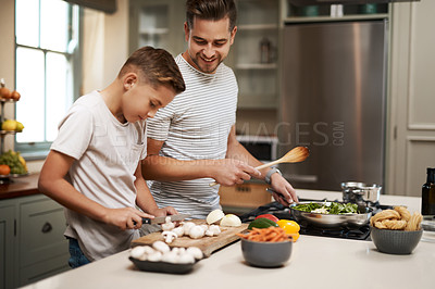 Buy stock photo Cropped shot of a young boy helping his father cook in the kitchen