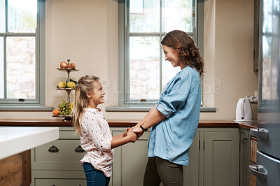 Buy stock photo Shot of a young girl and her mother dancing in the kitchen at home