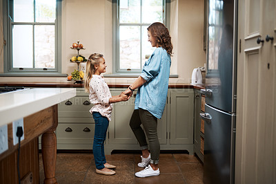 Buy stock photo Shot of a young girl and her mother dancing in the kitchen at home