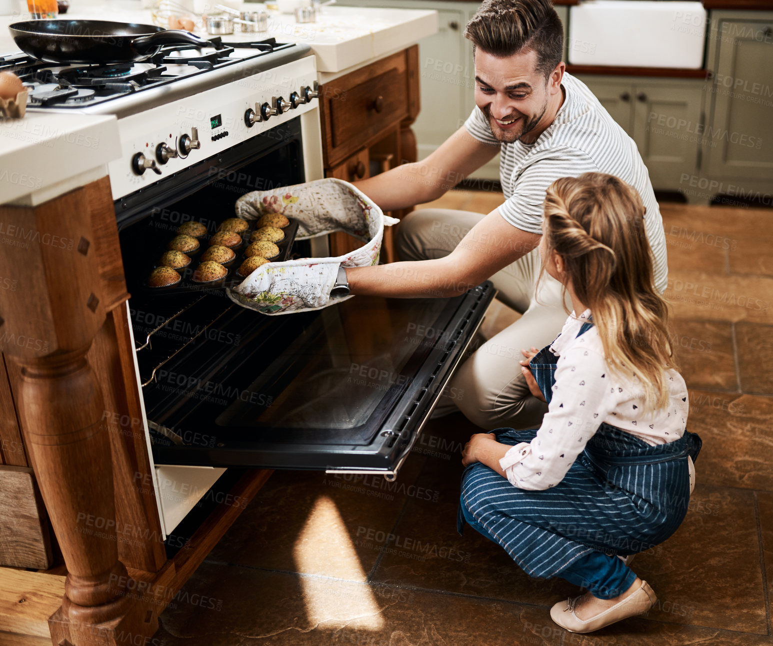 Buy stock photo Kitchen, family and father with child, oven and help in home with baking muffins with learning. Support, dessert and cooking with care, love and happy for youth development and bonding with smile