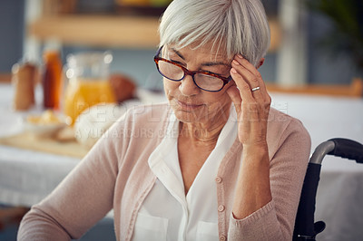 Buy stock photo Cropped shot of a senior woman suffering with a headache while sitting in her wheelchair in a retirement home